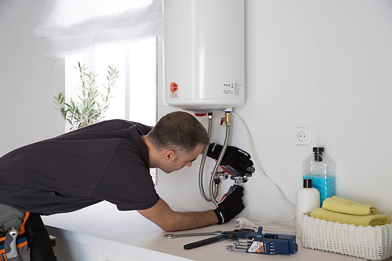 Técnico realizando instalación profesional de termo eléctrico en vivienda